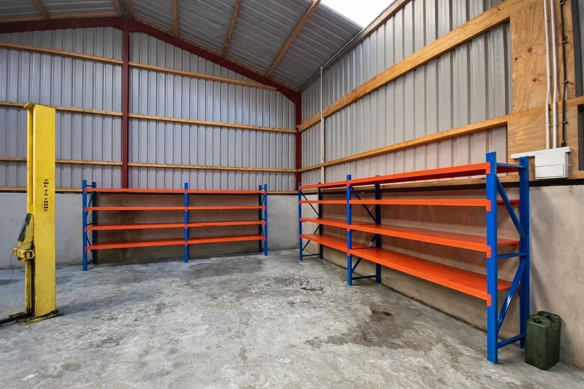 Taller mecánico con elevador y estanterías naranja y azul contra la pared